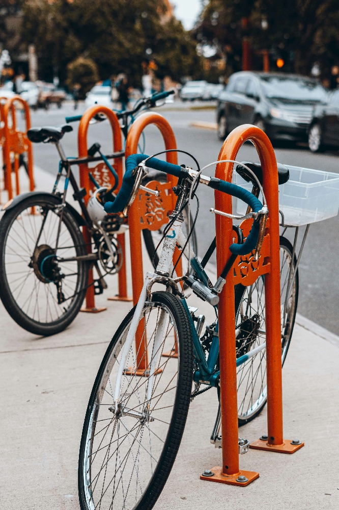 Bicycle properly parked and locked to a U-shaped bike rack on a city sidewalk showing correct positioning for security and stability